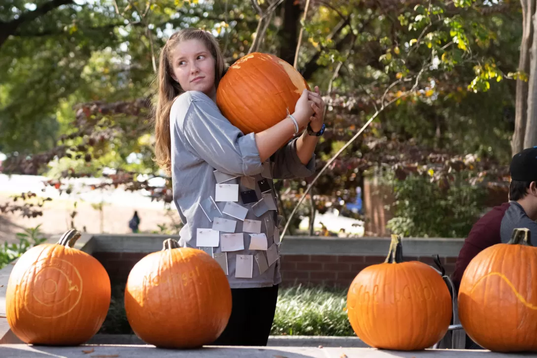 A student holds onto a pumpkin in preparation for the annual School of Physics Pumpkin Drop in 2018